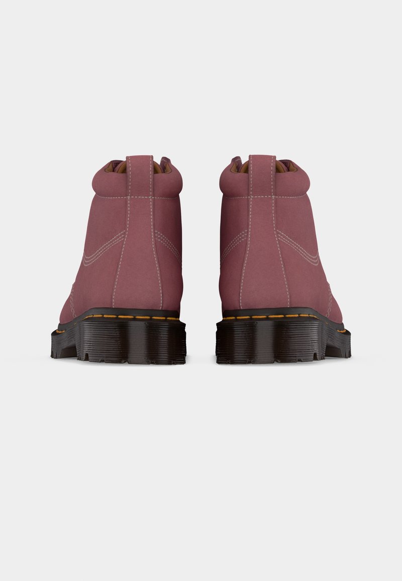 Pair of pink leather boots shown from the back with black thick soles and visible stitching, set against a plain light background.