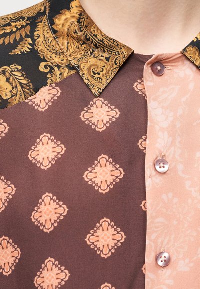 Πολύχρωμο πουκάμισο με μαύρο και χρυσό σχέδιο στο γιακά, ροζ και καφέ ύφασμα με λουλουδάτα μοτίβα και ροζ κουμπιά.