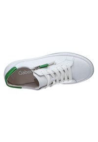 Witte leren sneaker met groene hielaccent, witte veters en een ritsdetail aan de zijkant. Gladde textuur en ronde vorm.