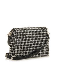 Schwarz-weiße Tweed-Handtasche mit einem Umhängeriemen, ausgestattet mit einem strukturierten Stoffmuster, silbernen Akzenten und einer rechteckigen Form.