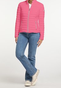 Růžová vyp padded bunda s vysokým límcem a zipovým zapínáním, se dvěma bočními kapsami, kombinovaná s modrými džíny a bílými teniskami.