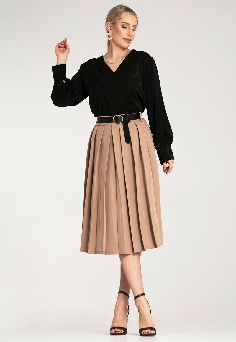 Czarna bluzka z dekoltem w serek z długimi rękawami, zestawiona z beżową plisowaną spódnicą, zwężoną w talii czarnym paskiem z złotą klamrą. Czarne sandały na obcasie.