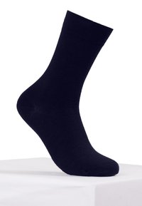 Calcetín de algodón azul marino, de longitud hasta la pantorrilla, con una textura suave, puño acanalado y puntera reforzada, exhibido sobre un pedestal blanco.