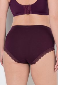 Ropa interior alta de algodón color burdeos con borde de encaje en las aberturas de las piernas. Textura suave con un diseño de cobertura total.