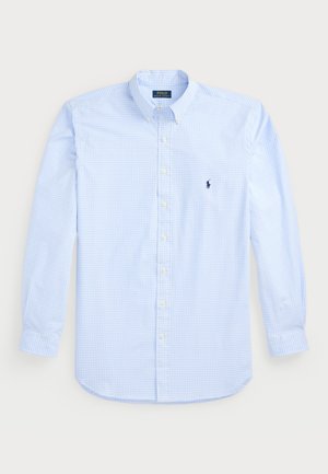 Chemise à manches longues à carreaux bleu clair avec col boutonné, boutons blancs et un petit logo navy sur la poitrine gauche. Matière en coton.