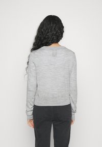 Pull gris à manches longues avec un col rond côtelé et une finition texturée. L'arrière présente une surface lisse et un ourlet légèrement cropped.