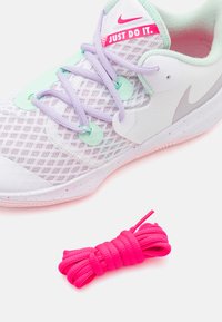 Vit Nike-sneaker med mintgröna och lavendelfärgade accenter, texturerat nätmaterial på ovandelen och prickig sula. Inkluderar en bunt rosa skosnören.
