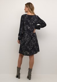 Schwarzes Blumenkleid mit langen Puffärmeln, Rundhalsausschnitt und knielangem Saum. Verfügt über ein dezentes Muster und eine fließende Silhouette.
