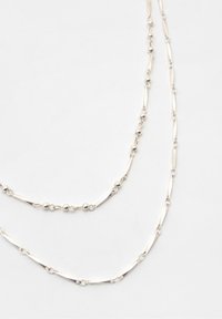 Collana a strati in argento con anelli allungati e perle rotonde alternate, con una finitura elegante e una texture liscia.