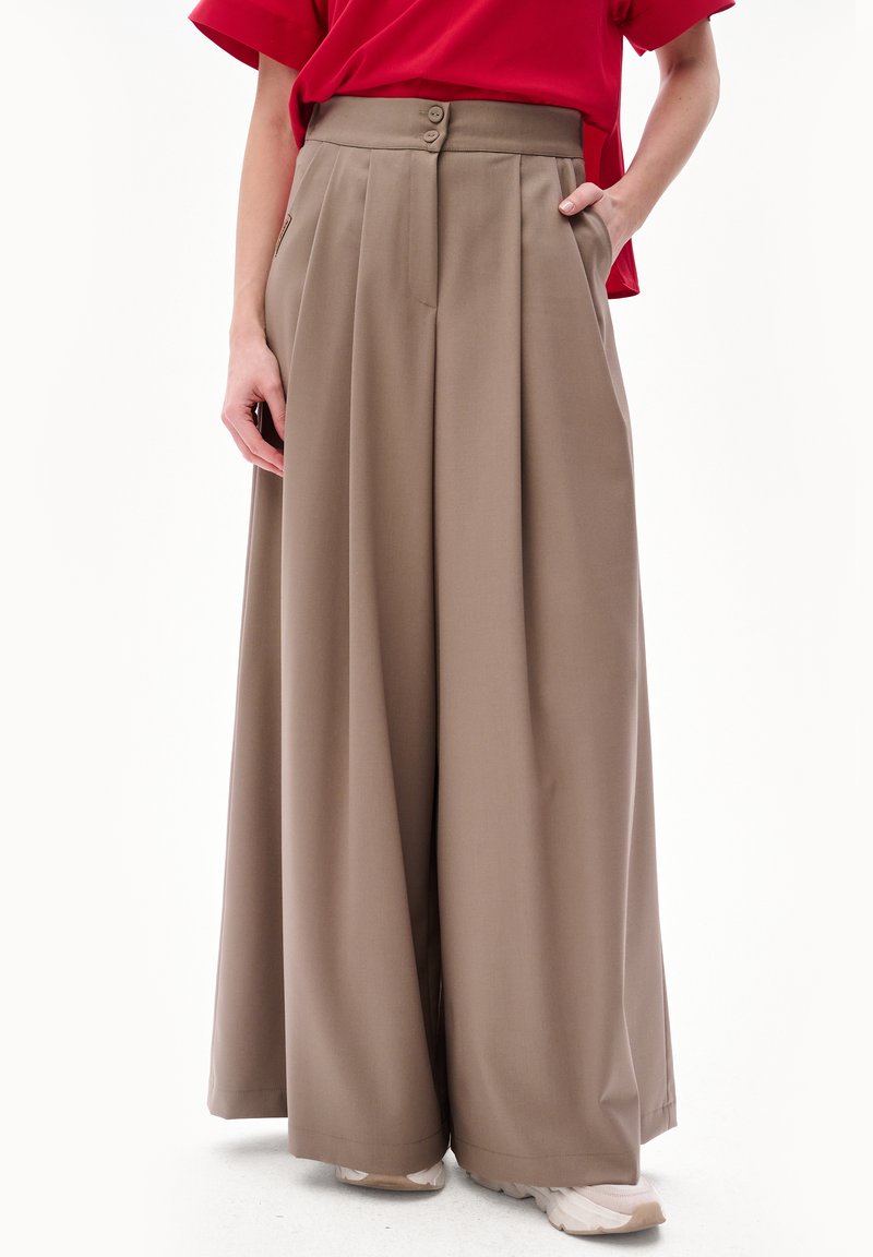 Beżowe spodnie szerokie z wysokim pasem, z dwoma guzikami i plisami, wykonane z lekkiego materiału. Zawierają boczne kieszenie.