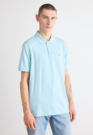 Polo bleu clair en coton, doté d'un col classique, de manches courtes et d'un petit logo brodé sur la poitrine.