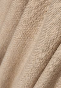 Beiger Strickstoff mit weicher Textur, der eine strukturierte Webart und einen sanften Fall zeigt, mit subtilen Farbnuancen.