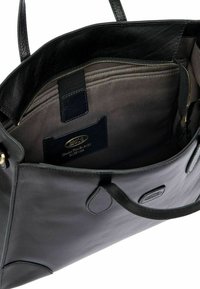 Borsa tote in pelle nera con una texture liscia, dotata di zip in tonalità oro, fodera khaki e numerose tasche interne per l'organizzazione.