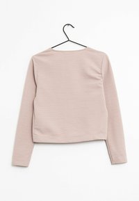 Różowy top z długim rękawem wiszący na czarnym haczyku. Tkanina ma prążkowaną fakturę, zaokrąglony dekolt i dopasowany krój.