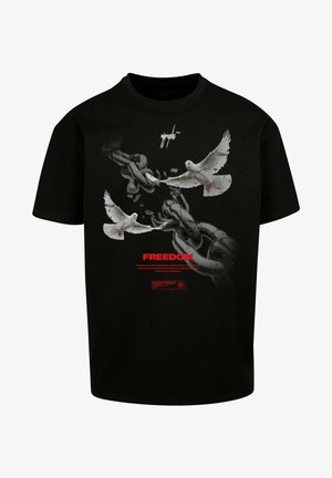 Mustmust valge t-särk, millel on graafika kahest valgest tuvist, kes purustavad ahelaid. Tekst sisaldab sõna "VABADUS" punases, koos täiendavate märkidega all.