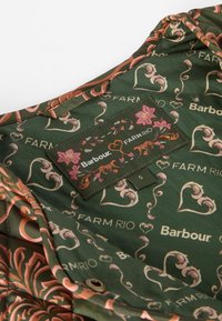 Green fabric with floral patterns and logos. Includes a tag with "Barbour" and "FARM RIO." Smooth texture, showcasing intricate design details.