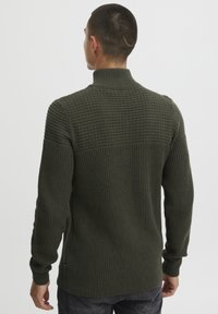 Grüner gestrickter Pullover mit hohem Kragen, strukturierten Mustern auf den Schultern, eng anliegenden Bündchen und einem leicht verlängerten Rückensaum.