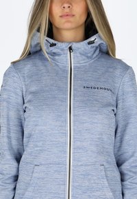 Light blue zip-up hoodie made of textured fabric, featuring a high collar, drawstring hood, and pockets. "SWEDEMOUNT" logo on chest.
