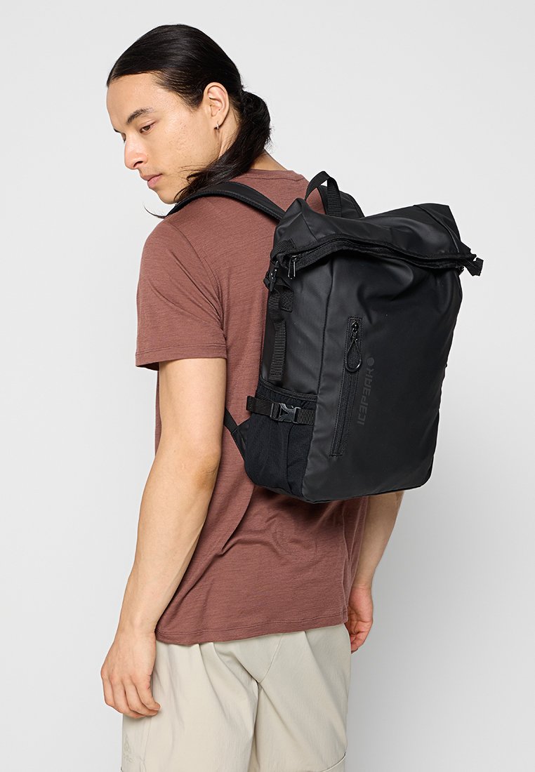 Czarny plecak o konstrukcji typu roll-top, wykonany z materiału tekstylnego, z regulowanymi ramionami i przednią kieszenią na zamek. Zauważalne teksturowane boczne panele oraz detal z logo.