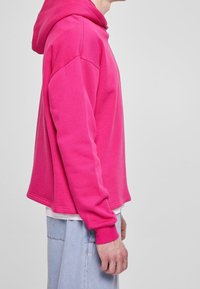 Felpa con cappuccio rosa, maniche lunghe, vestibilit�à morbida, polsini a costine e tasca a marsupio, abbinata a pantaloni shorts in denim chiaro.