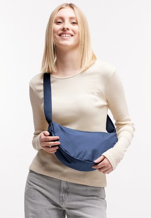 Navyblauer Sling-Rucksack aus strapazierfähigem Stoff mit weicher Textur. Verfügt über einen breiten Gurt und ein minimalistisches Design. Logo an der Vorderseite sichtbar.