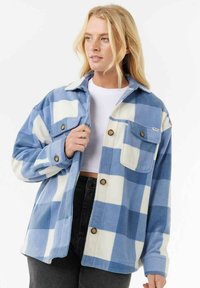 Fleece shirt jacket met een blauw-witte ruitpatroon. Bevat een kraag, voorknopen en twee borstzakken met ronde kleppen.