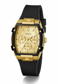 Orologio rettangolare color oro con cinturino in gomma nera texturizzata, caratterizzato da tre sottodial e marcatori delle ore bold; ulteriori dettagli in oro.