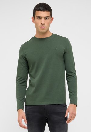 Koszulka z długim rękawem i okrągłym dekoltem w kolorze ciemnej zieleni, wykonana z bawełny, z subtelnym logo na piersi, zestawiona z ciemnymi dżinsami.