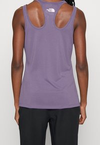 Fioletowy sportowy top na ramiączkach z designem typu racerback, wykonany z gładkiego materiału. Posiada małe białe logo z tyłu oraz kontrastowe szwy.
