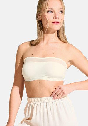 Haut bandeau crème sans bretelles avec une texture lisse et des accents transparents, associé à un pantalon clair et ample.