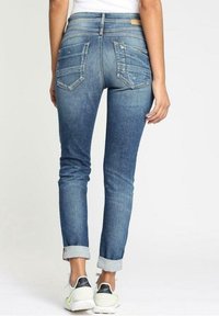 Modré denimové džíny s úzkým střihem, středně vysokým pasem, ohrnutými manžetami a dvěma zadními kapsami s jemným prošíváním.