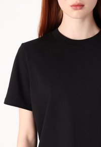 Sort bomulds T-shirt med rund halsudskæring, korte ærmer og en glat tekstur. Har et enkelt, udekoreret design.
