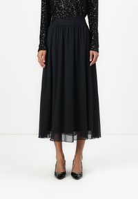 Čierna chiffon midi sukňa so zberaným pásom, ktorá má vzdušný strih a polpriehľadný povrch na leme. V kombinácii s lesklými čiernymi lodičkami.
