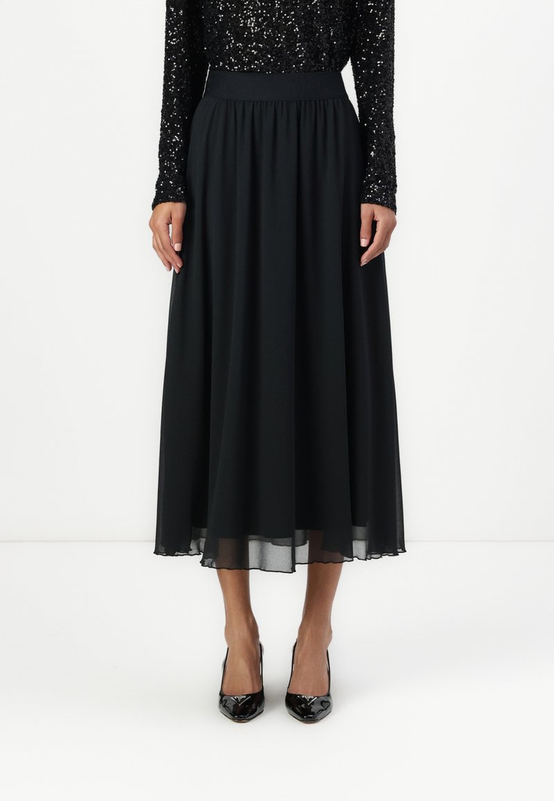 Čierna chiffon midi sukňa so zberaným pásom, ktorá má vzdušný strih a polpriehľadný povrch na leme. V kombinácii s lesklými čiernymi lodičkami.