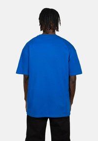 Sininen lyhythihainen t-paita rentoa istuvuutta, valmistettu pehmeästä puuvillasta. Ominaisuuksiin kuuluu pyöreä kaula-aukko ja sileä tekstuuri, näkyy takaa.