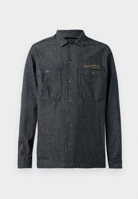 Camicia in denim scuro con bottoni, decorata da strisce verticali e due tasche sul petto, logo ricamato in oro sul lato sinistro. Bottoni a pressione in metallo.