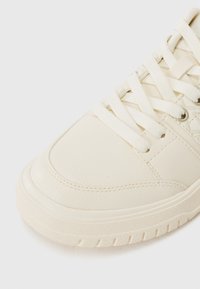 Baskets en cuir crème avec bout rond, semelle épaisse texturée, lacets plats et détails cousus. Fini lisse avec des accents minimaux.