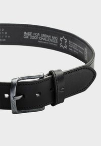 Zwarte leren riem met een gestructureerde afwerking, metalen gesp en verstelbare gaatjes; bevat branding en onderhoudsinstructies aan de binnenkant.