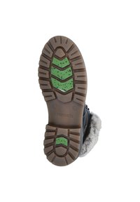 Zwarte zool van een laars met een geweven rubberafwerking, voorzien van een groen en zwart traingsdesign. Inclusief een bontaccent op de hiel.