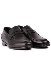Black leather loafers with a smooth finish, featuring a decorative strap and low heel. Classic design with stitching details on the upper.