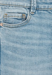 Ljusblå denimtyg från jeans som visar detaljerad sömnad och en liten framficka. Texturen är mjuk med ett klassiskt diagonalvävt mönster.