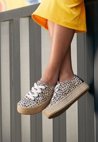 Leopard-print platform sneakers with white laces, canvas material, textured jute sole, rounded toe, and contrasting sole design.