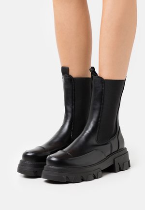 Czarne skórzane botki za kostkę z elastycznymi panelami bocznymi, okrągłym noskiem, masywną gumową podeszwą o ryflowanym wzorze oraz pętlami do ściągania.