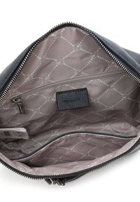 Zwarte leren tas interieur, heeft een lichtgrijs voering met een geometrisch patroon, een ritsvak en een getextureerd etiket.