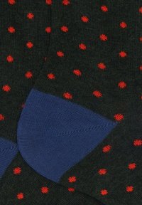 Calze verde scuro con pois rossi, caratterizzate da un bordo a coste blu uniforme. La trama appare morbida e lavorata a maglia con una finitura liscia.