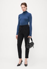 Μπλε λαιμόκοψη, μαύρα παντελόνια με λεπτή γραμμή και κορδόνι στη μέση, και μαύρη τσάντα με καρφιά, συνδυασμένα με μαύρες γόβες με μυτερή μύτη.