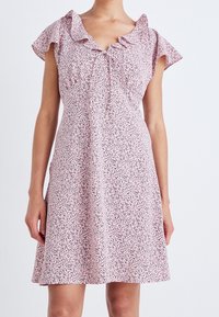 Kurzes pinkes Kleid mit einem gerafften Ausschnitt und kurzen Ärmeln, das ein verstreutes Muster aus schwarzen und pinken Punkten aufweist.