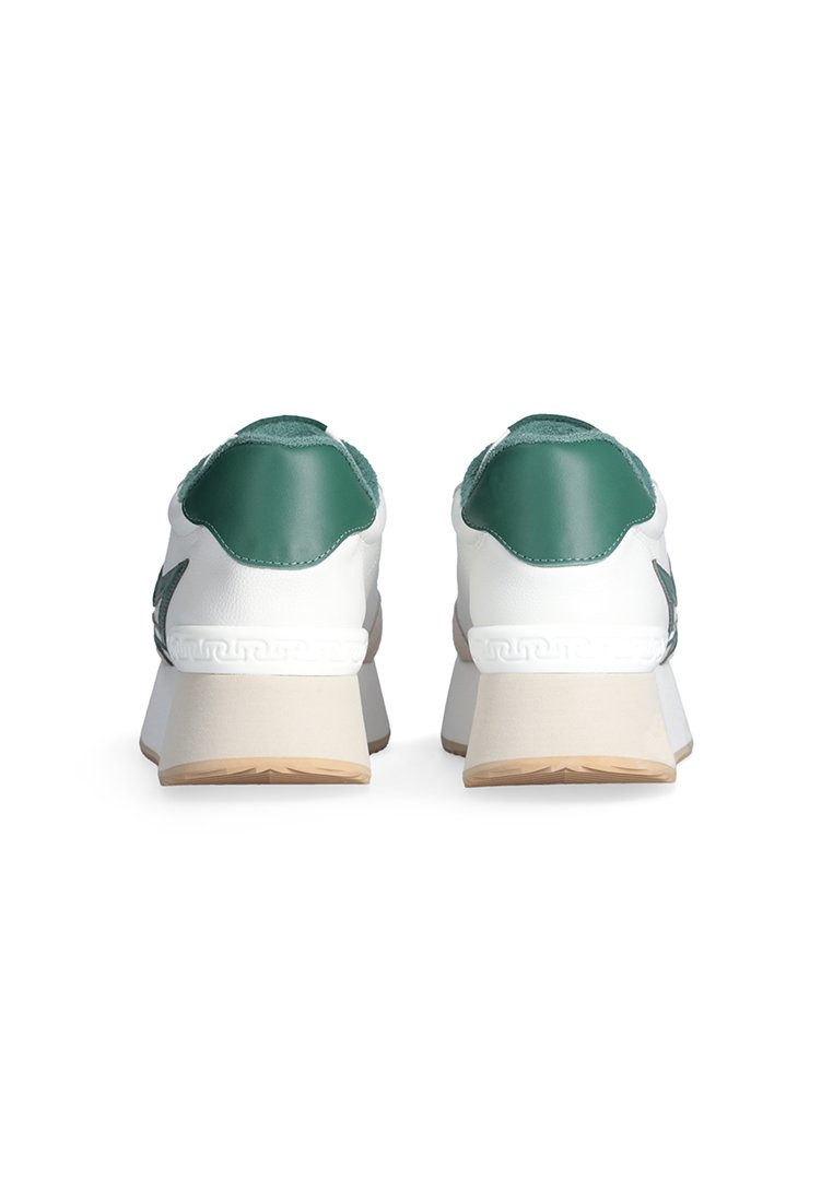 Un par de zapatillas blancas con talones verdes y suelas beige, vistas desde atrás, sobre un fondo blanco.