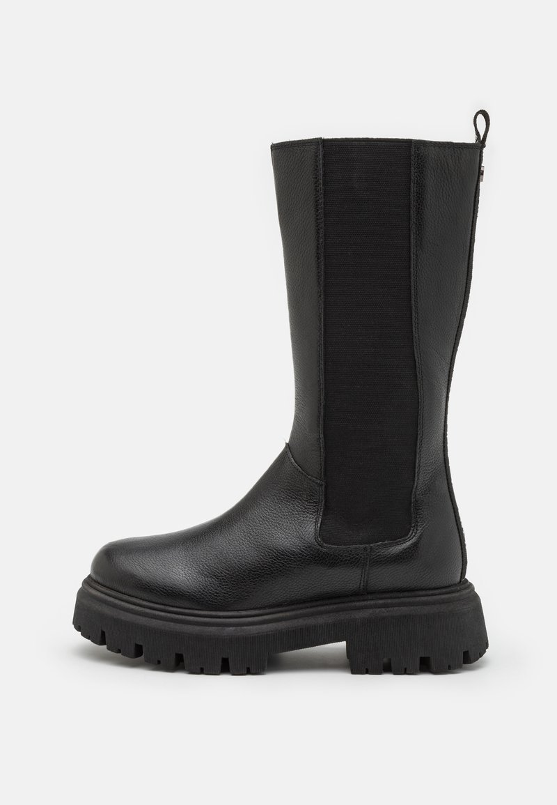 Botte noire hauteur genou avec un extérieur en cuir lisse et des panneaux élastiques sur les côtés. Elle dispose d'une semelle en caoutchouc épaisse avec des profondes rainures pour une adhérence optimale.