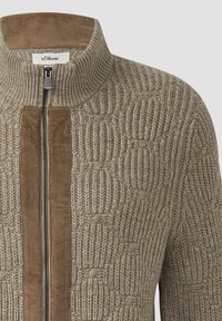 Beige gebreide zip-up trui met een hoge kraag, voorzien van corduroy accenten langs de voorkant van de rits en een gestructureerd patroon.